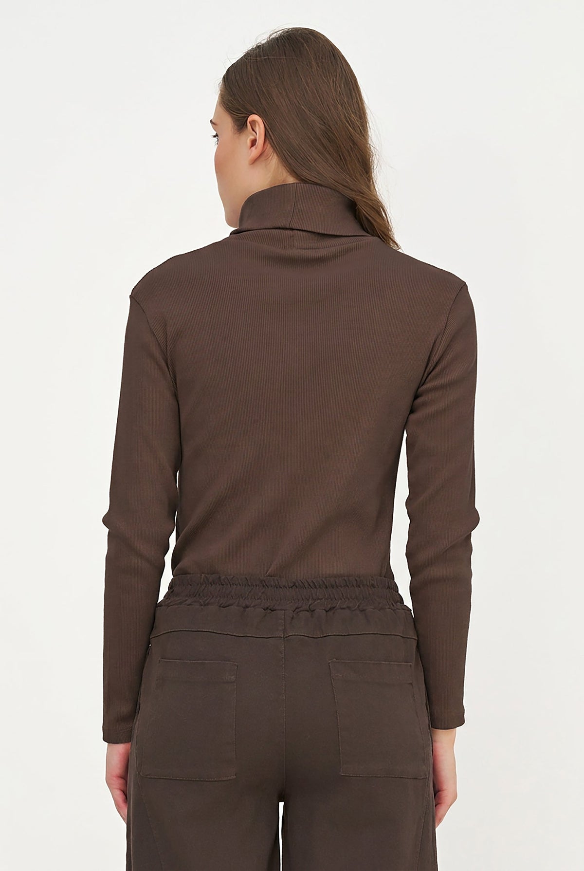 A woman shown from the back wearing a dark brown long-sleeve mock neck top and matching brown pants against a plain white studio background.