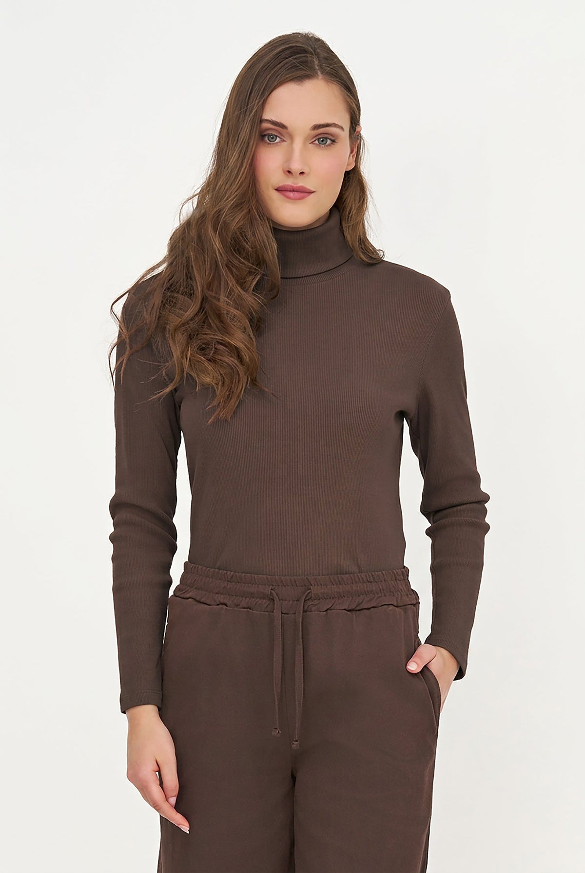 A woman modeling a dark brown long-sleeve mock neck top and matching brown drawstring sweatpants against a plain white studio background.