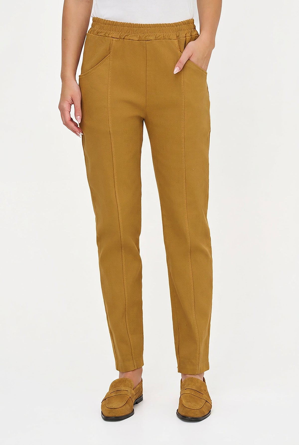 A person wearing slim-fit mustard yellow trousers with side pockets and a matching pair of loafers, shown from the waist down against a plain white studio background.