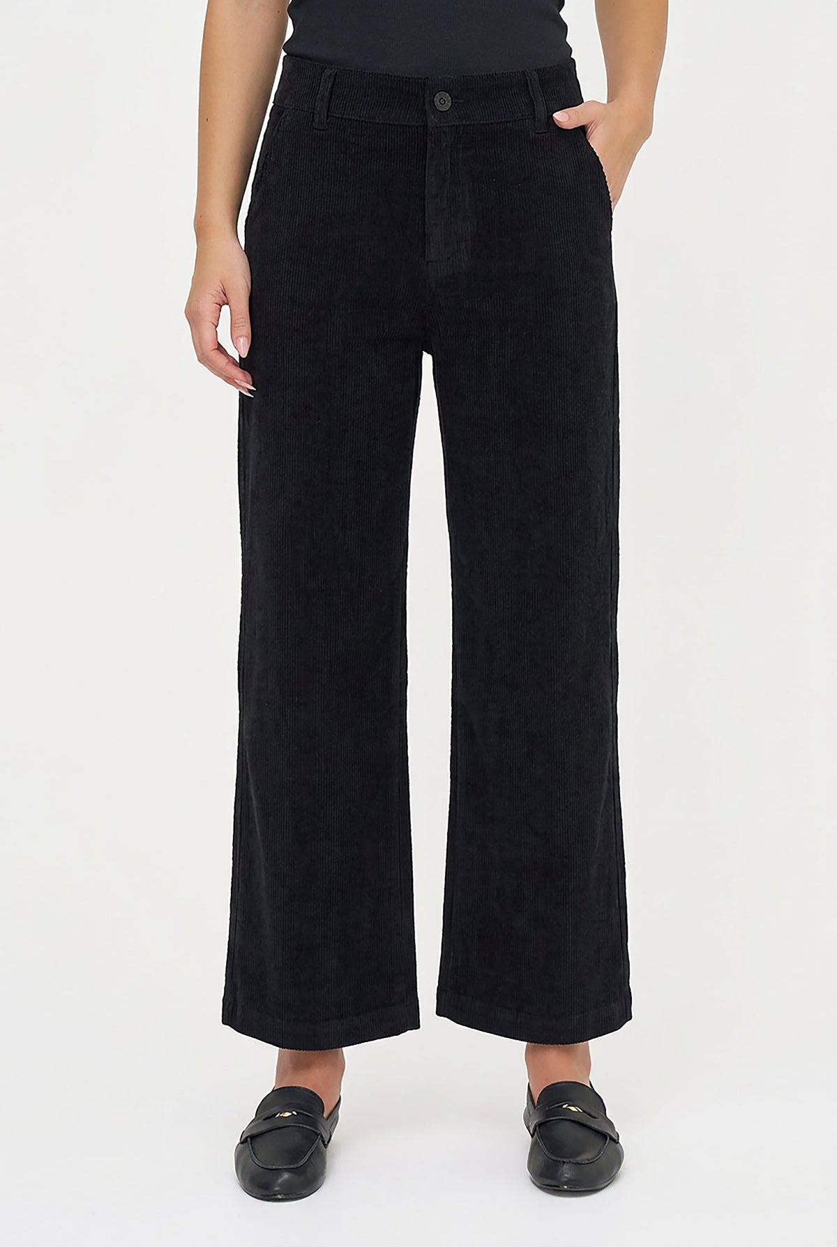 A model wearing black wide-leg corduroy trousers, paired with black loafers, shown from the waist down on a plain white studio background.