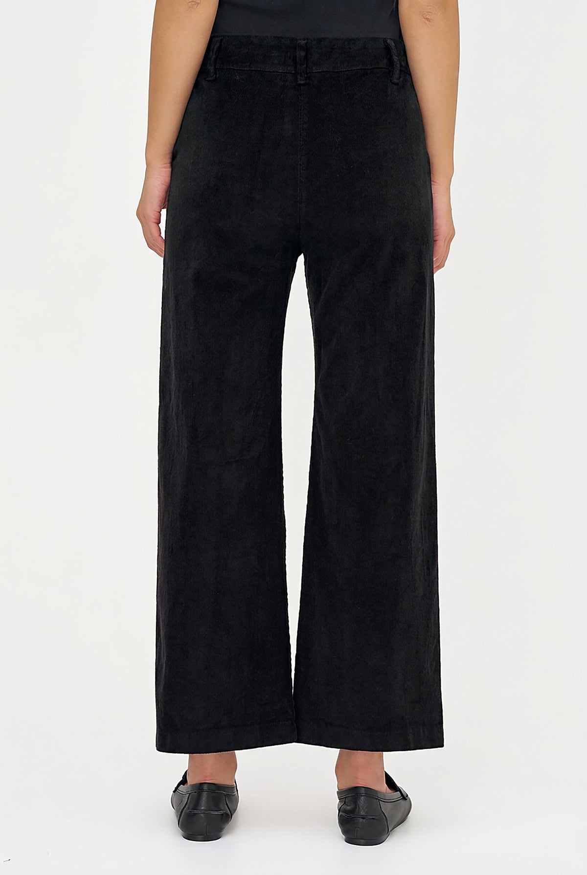 A person shown from the waist down wearing black wide-leg cropped pants and black flats against a plain white studio background.