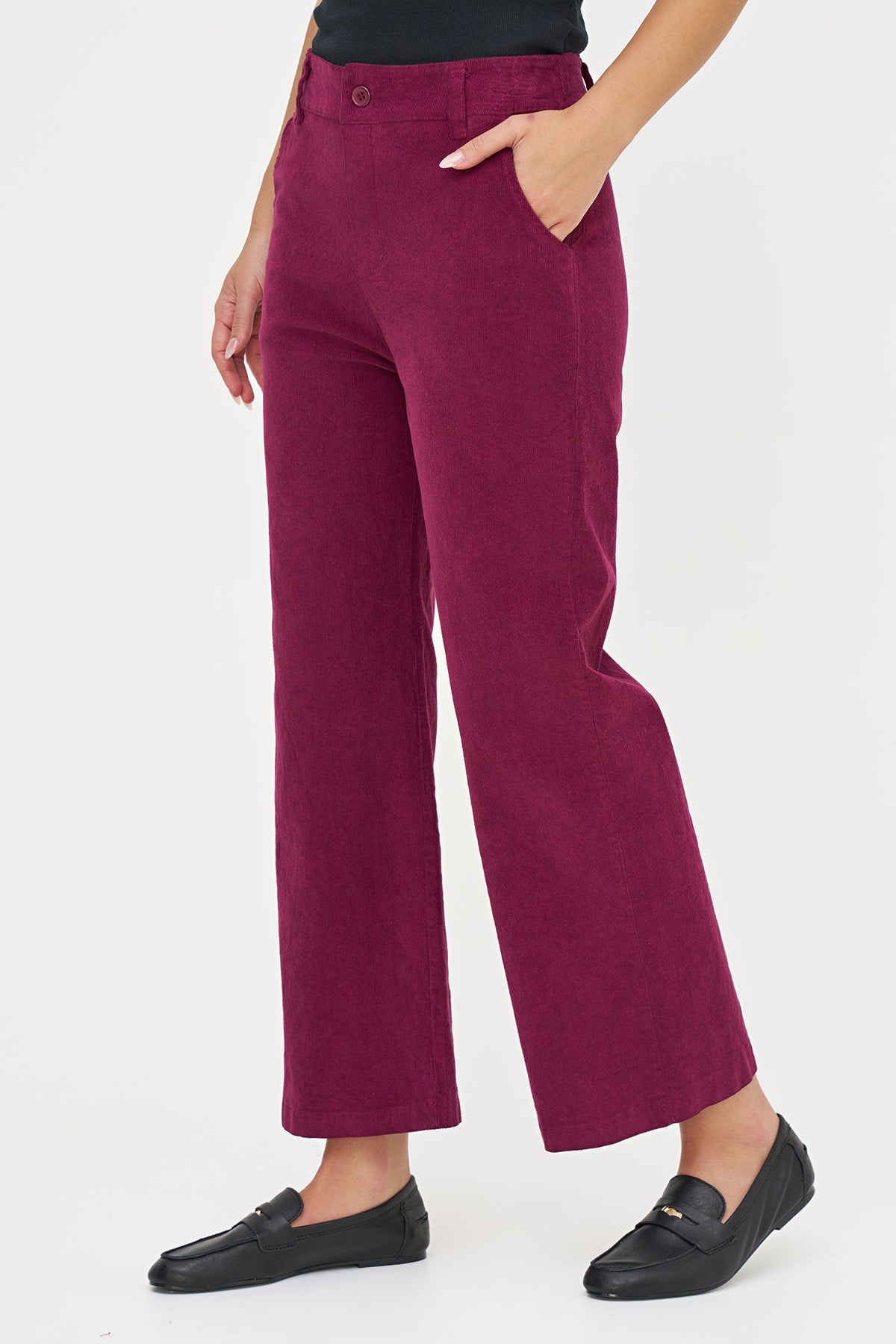 A person wearing high-waisted, wide-leg corduroy trousers in a deep berry or burgundy shade, paired with black loafers, shown against a plain white studio background.