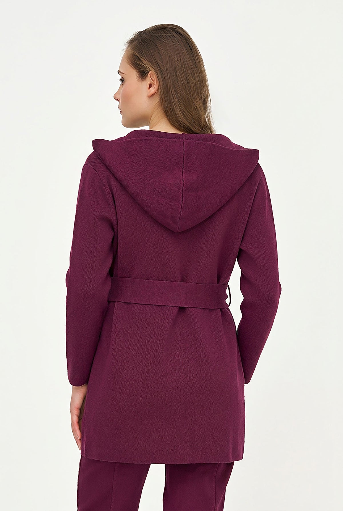 A woman shown from the back wearing a deep plum purple hooded coat with a matching waist belt, photographed against a plain white studio background.