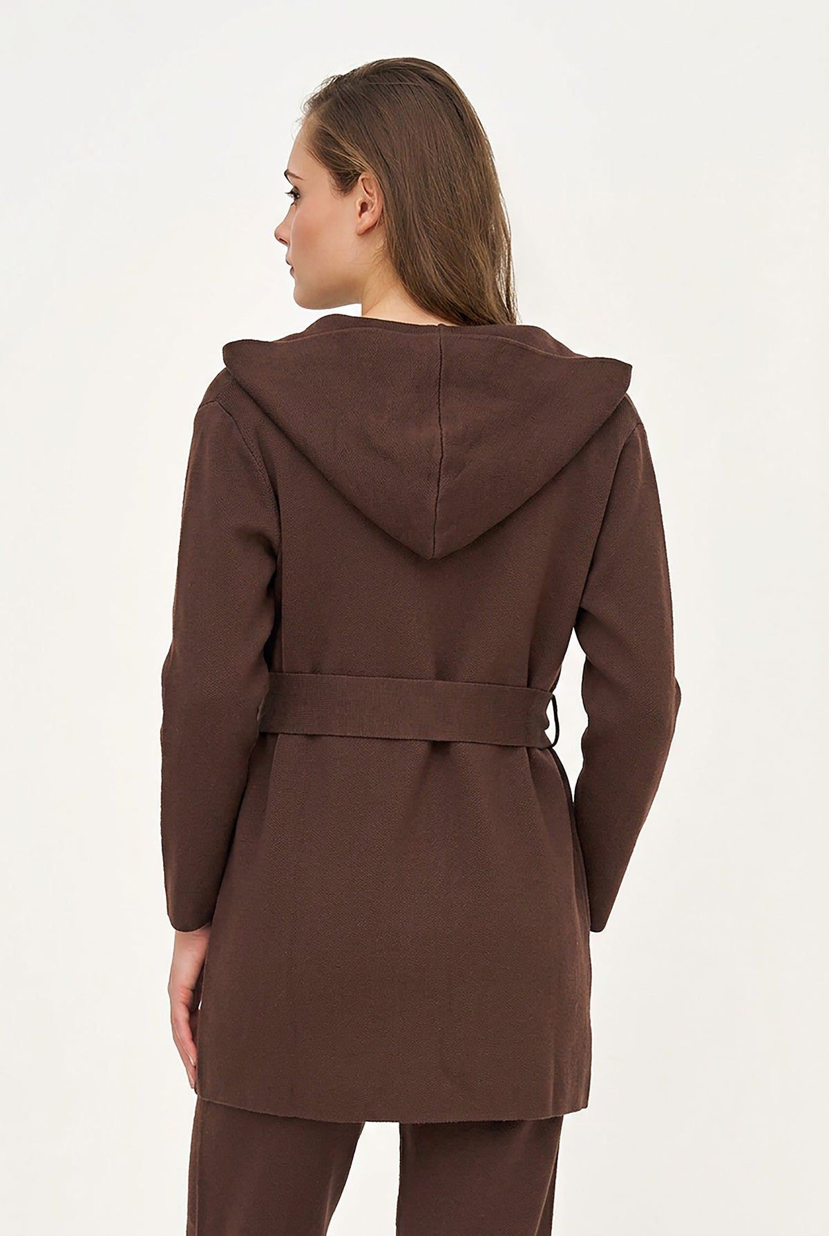A woman shown from the back wearing a brown hooded coat with a matching belt and brown pants against a plain light background.