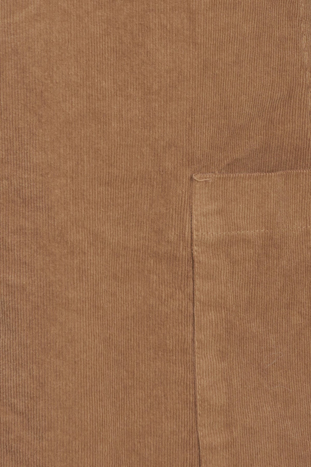 Close-up of a brown corduroy fabric with a visible pocket seam and ribbed texture.