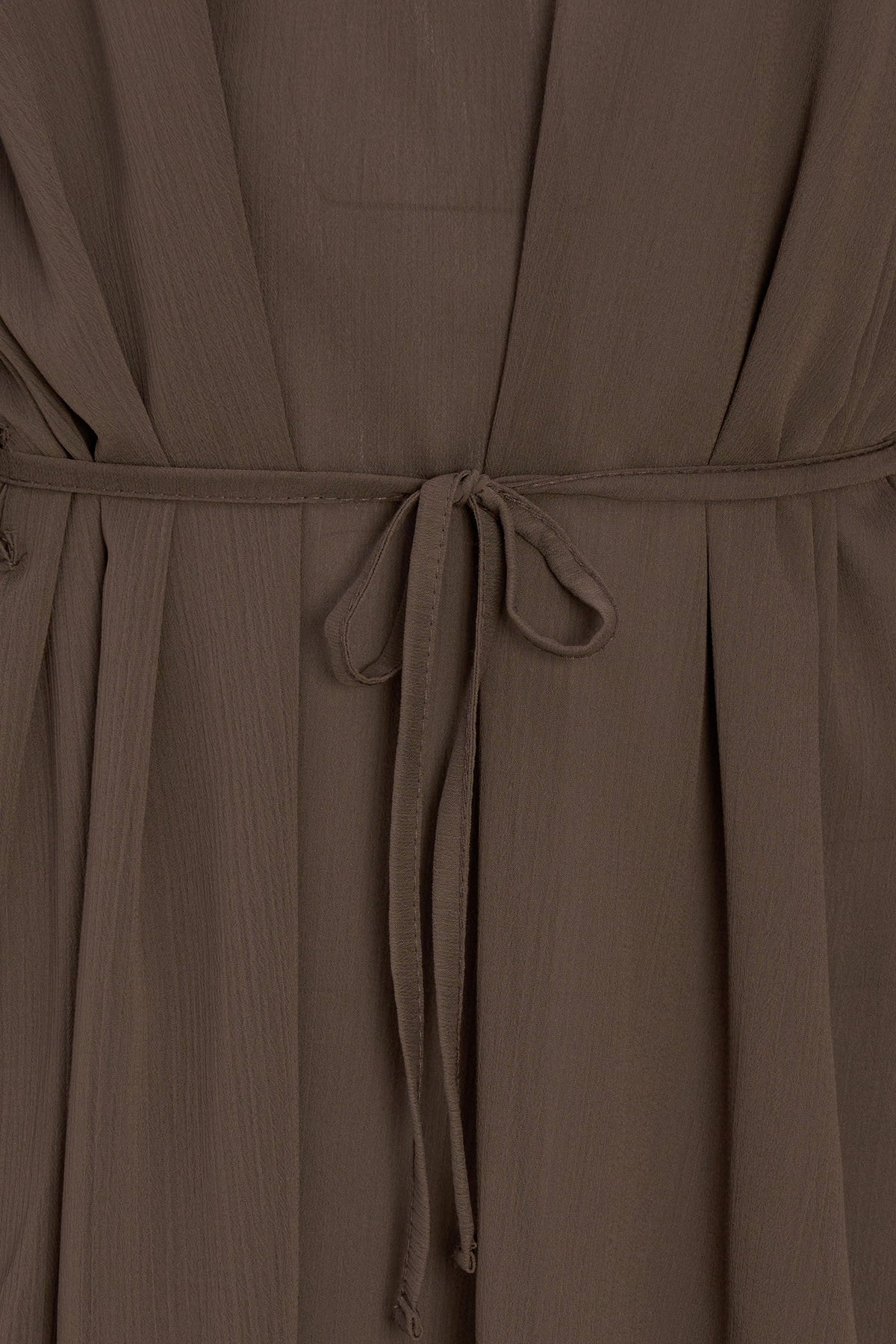 Close-up of a brown wrap dress with a tie belt, showing the textured fabric and waist details.