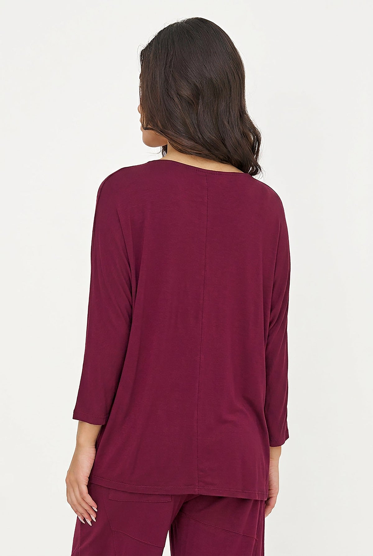A woman shown from the back wearing a long-sleeve burgundy top and matching pants against a plain white background.