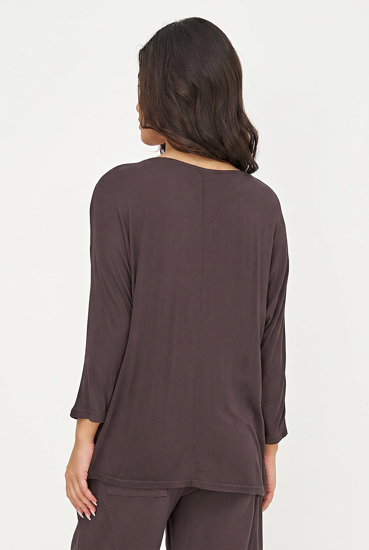 A woman viewed from the back wearing a dark brown long-sleeve top and matching pants against a plain white studio background.