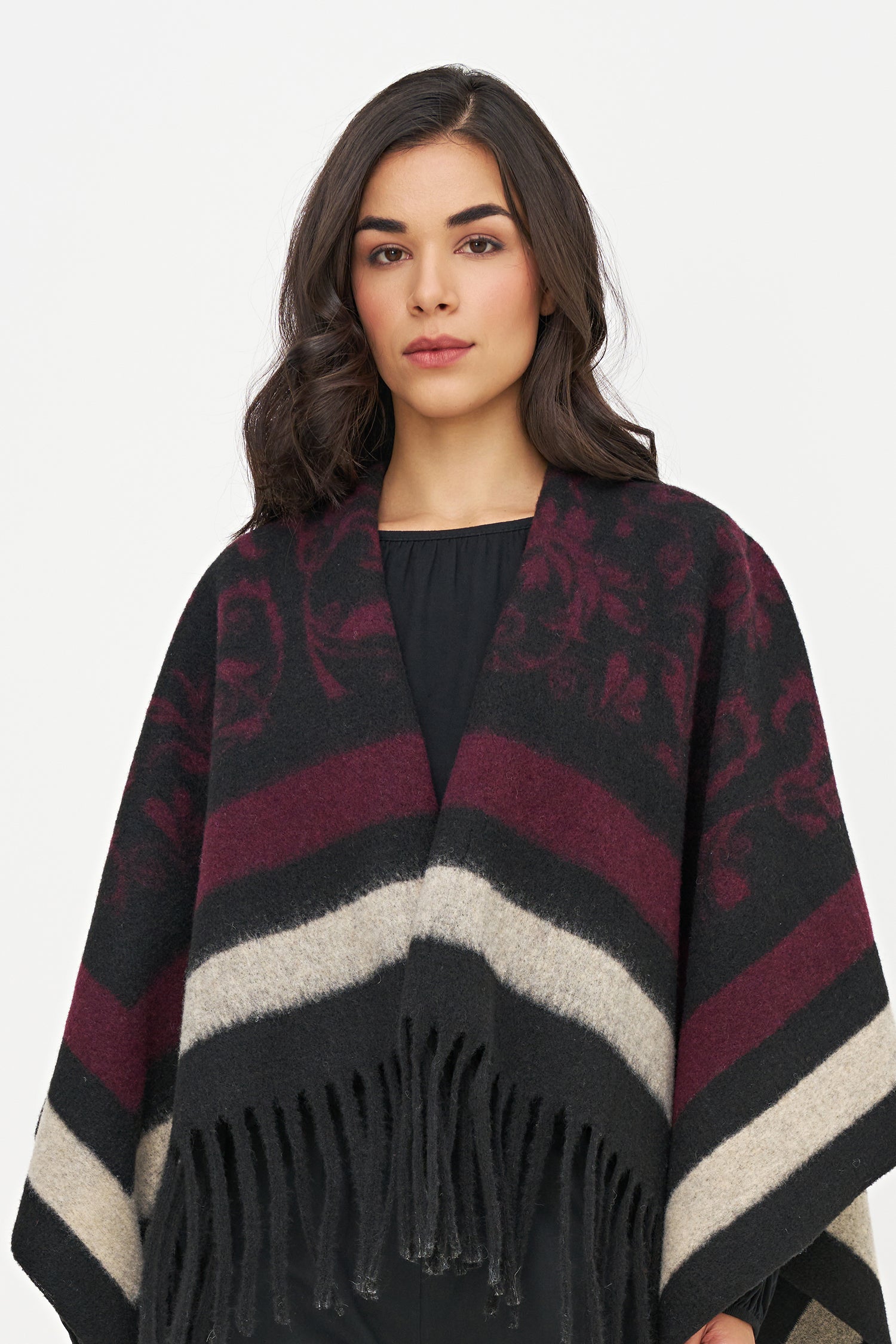 Woman wearing a patterned poncho with fringes on a white background