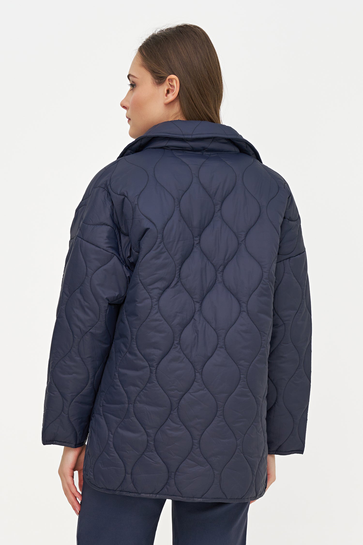 Woman wearing a navy quilted jacket on a white background