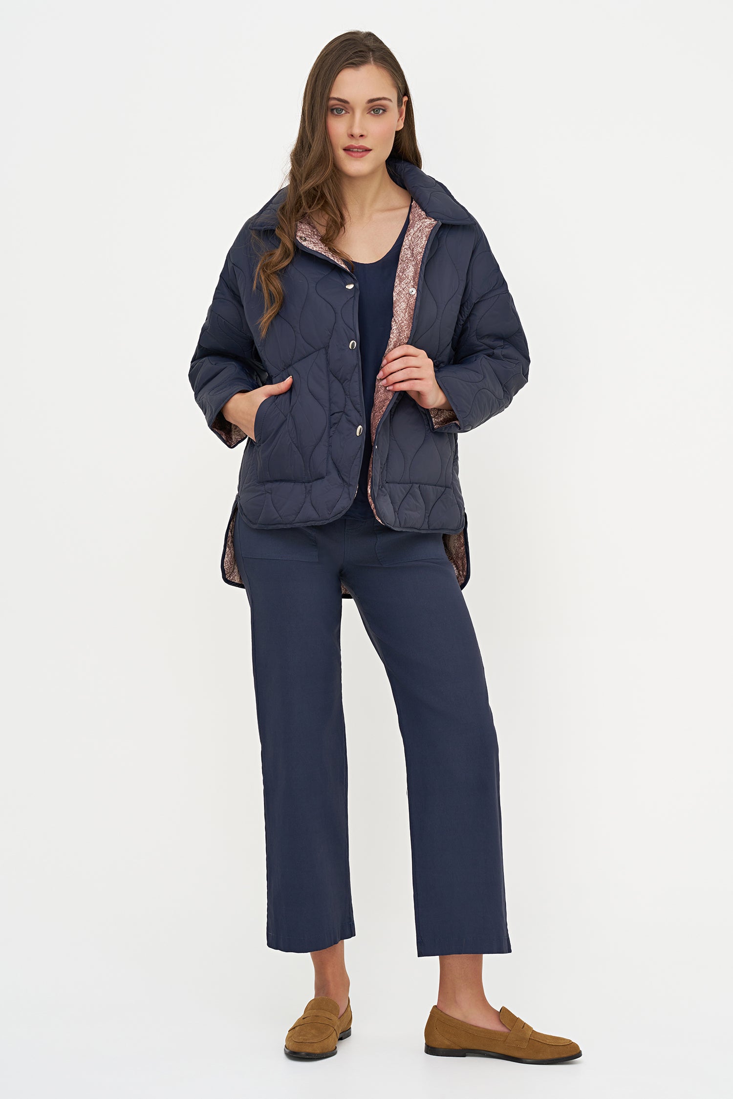 Woman wearing a navy quilted jacket and pants on a white background