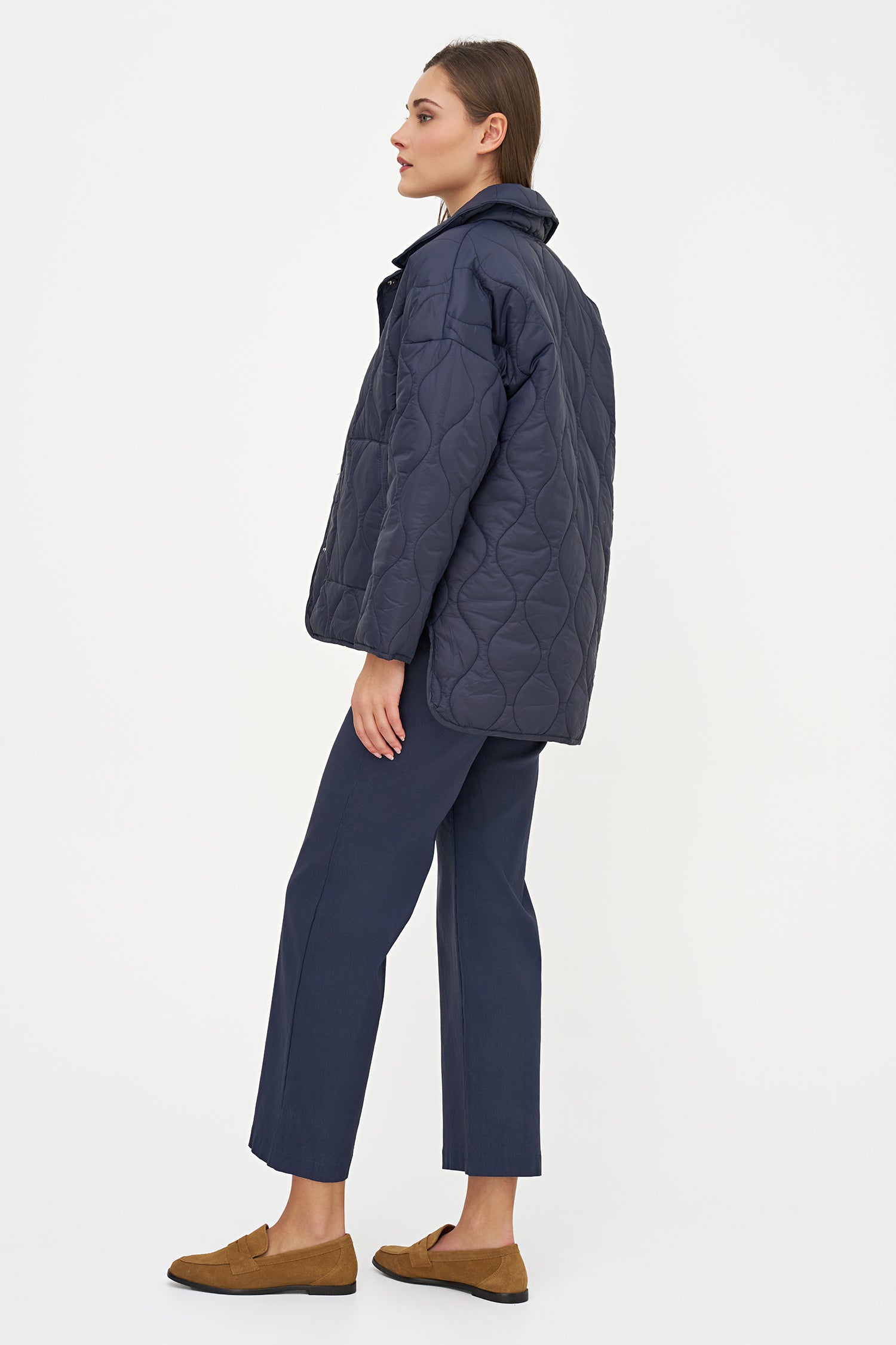 Woman wearing a dark blue quilted jacket and pants on a white background
