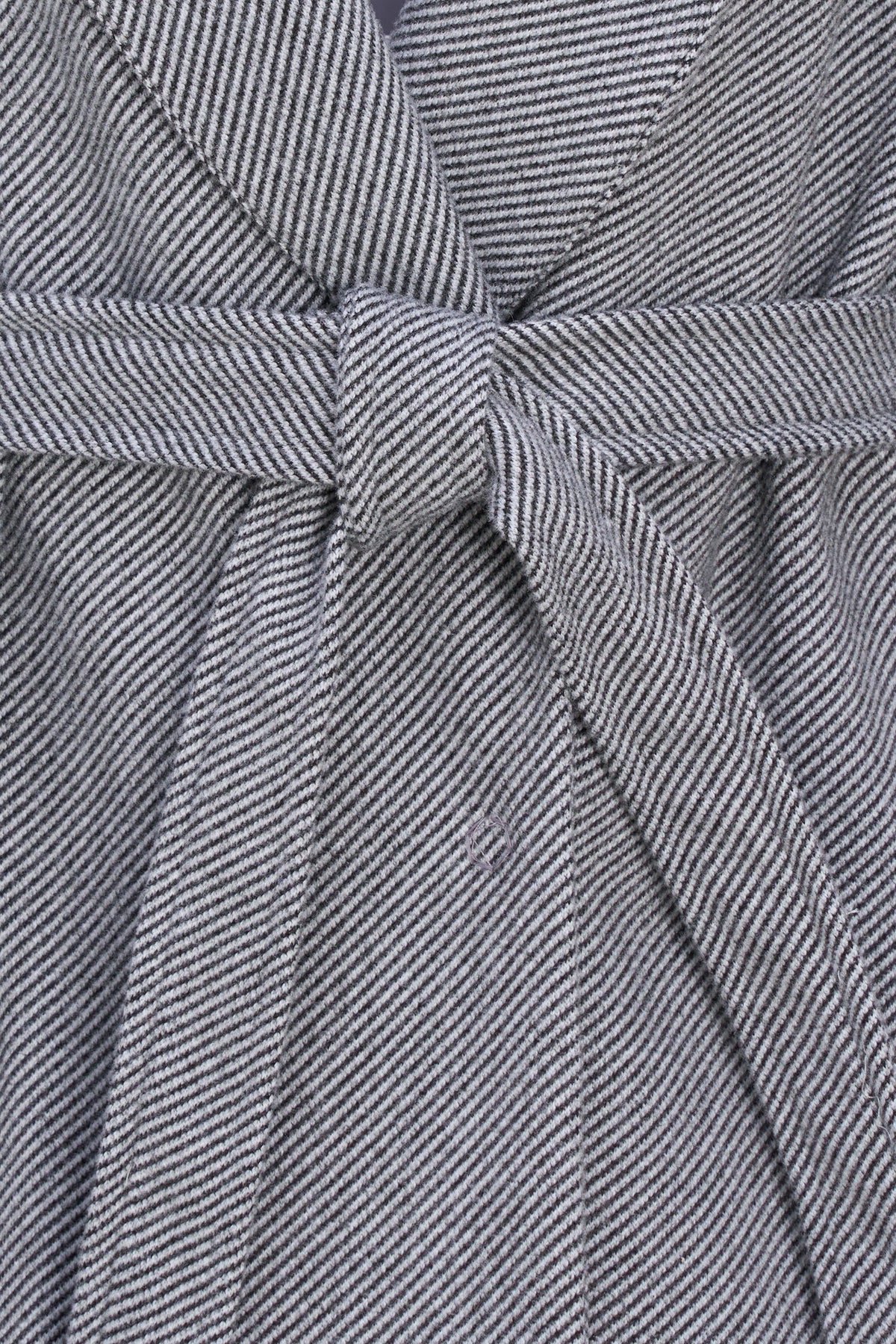 Close-up of a gray and white micro-houndstooth patterned fabric with a matching tie belt, showing the detailed woven texture.