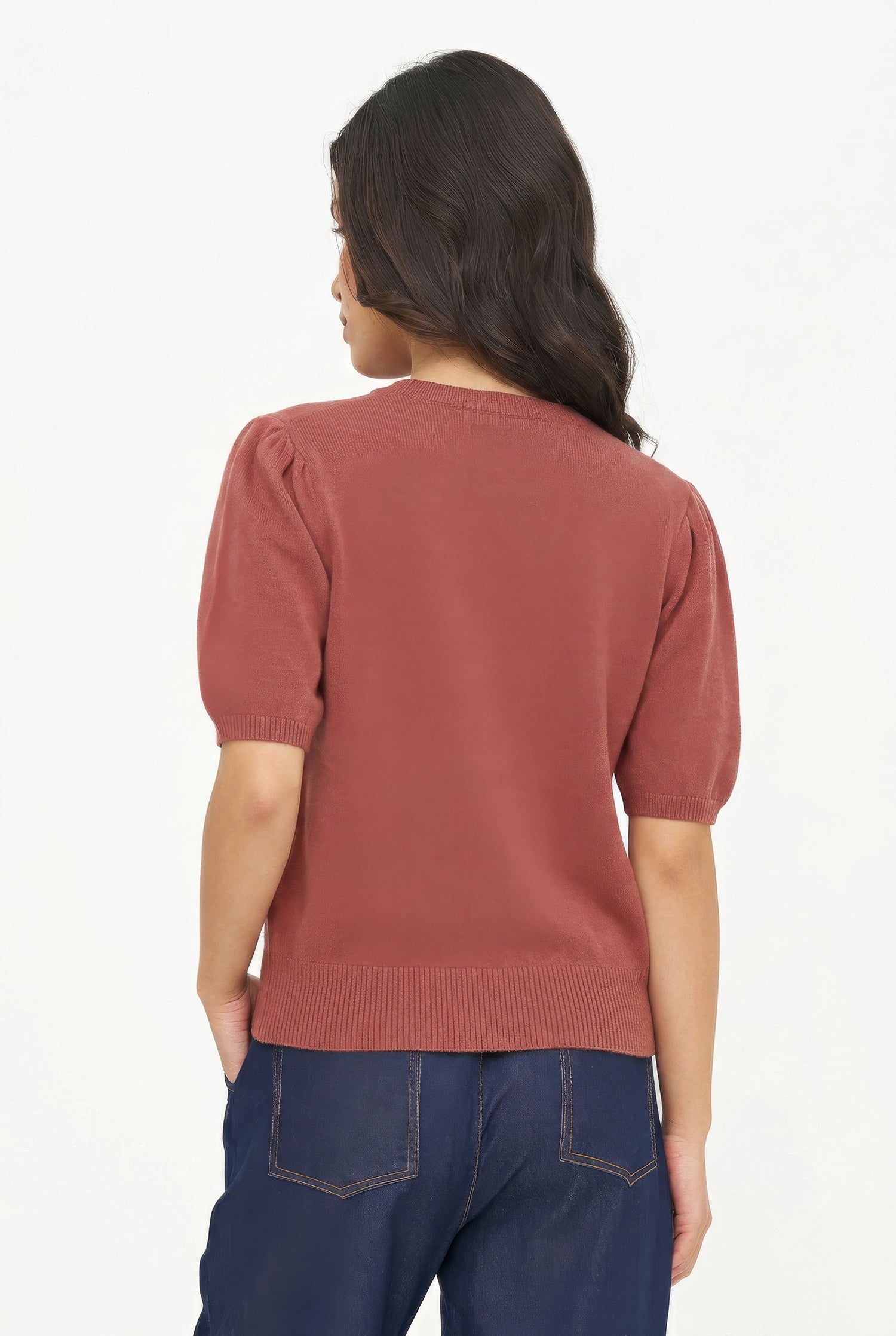 Person wearing a rust-colored sweater and blue jeans on a white background