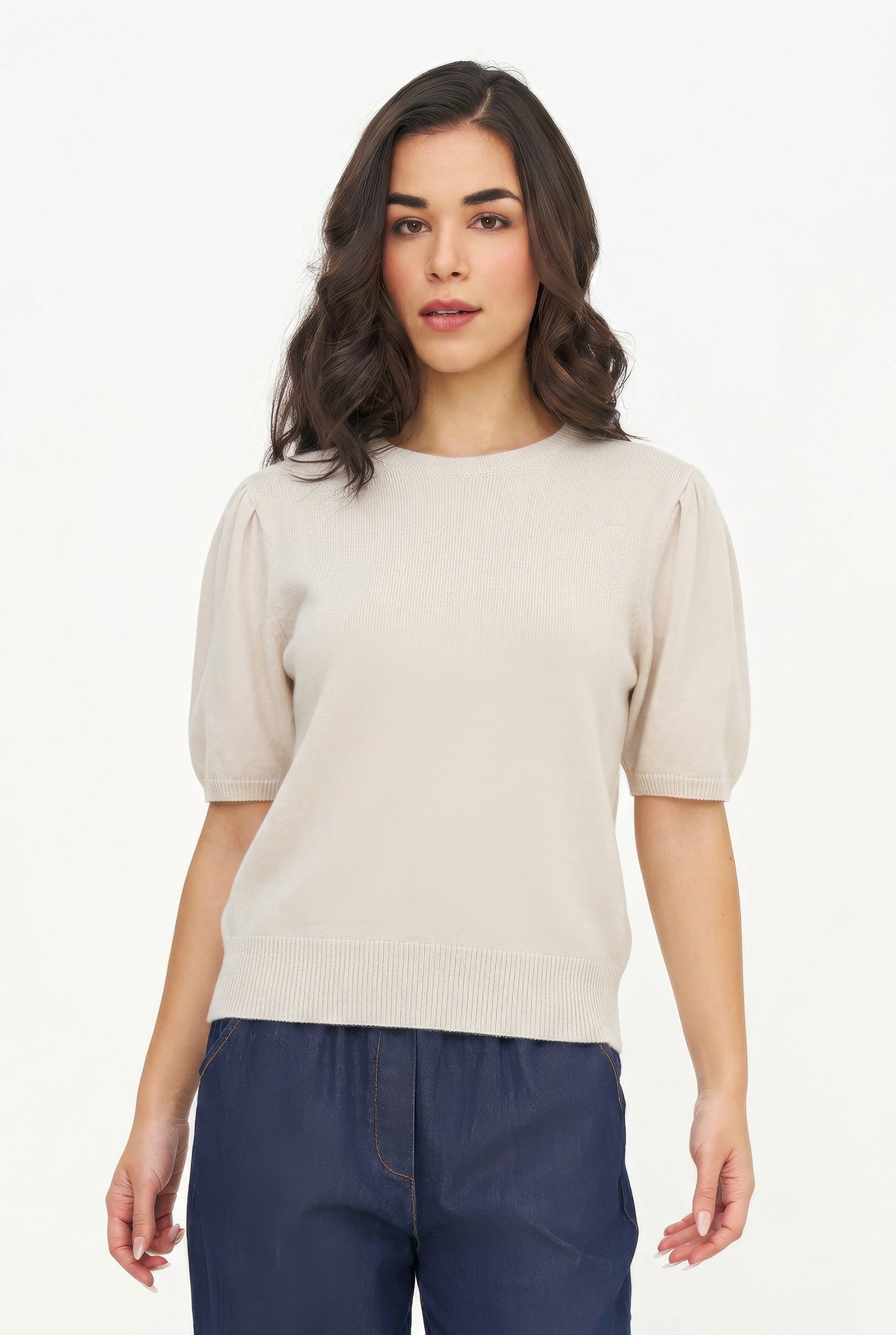 Woman wearing a beige sweater and blue pants on a white background