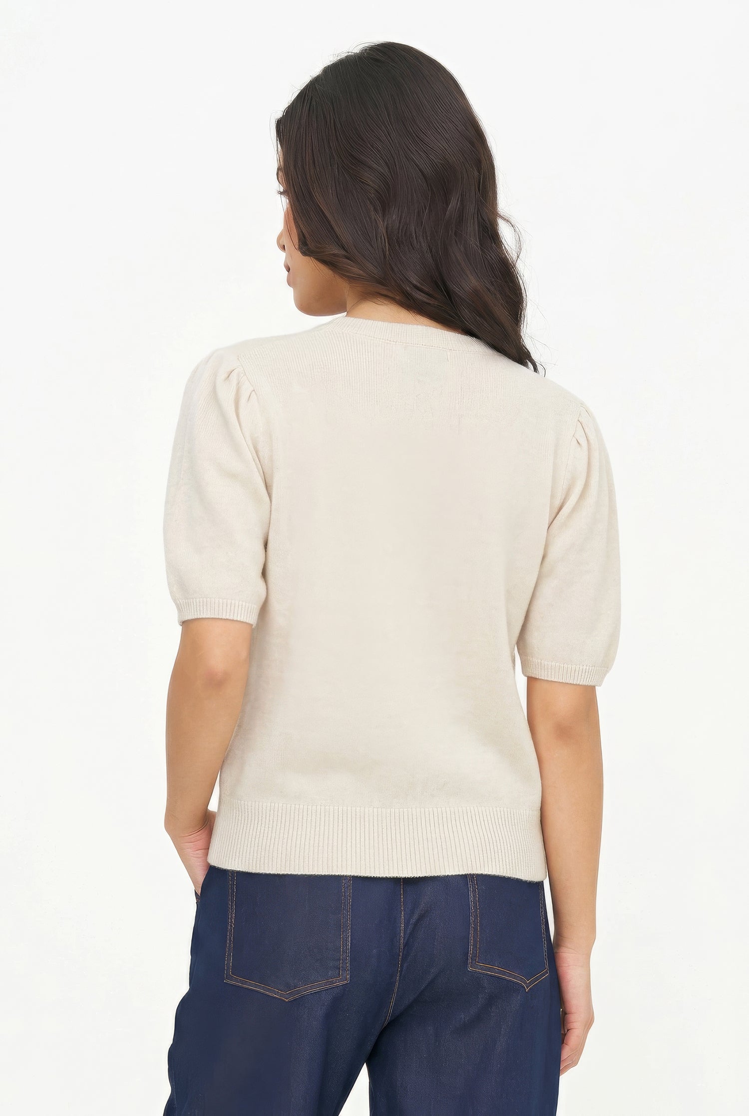 Person wearing a beige sweater and blue jeans on a white background