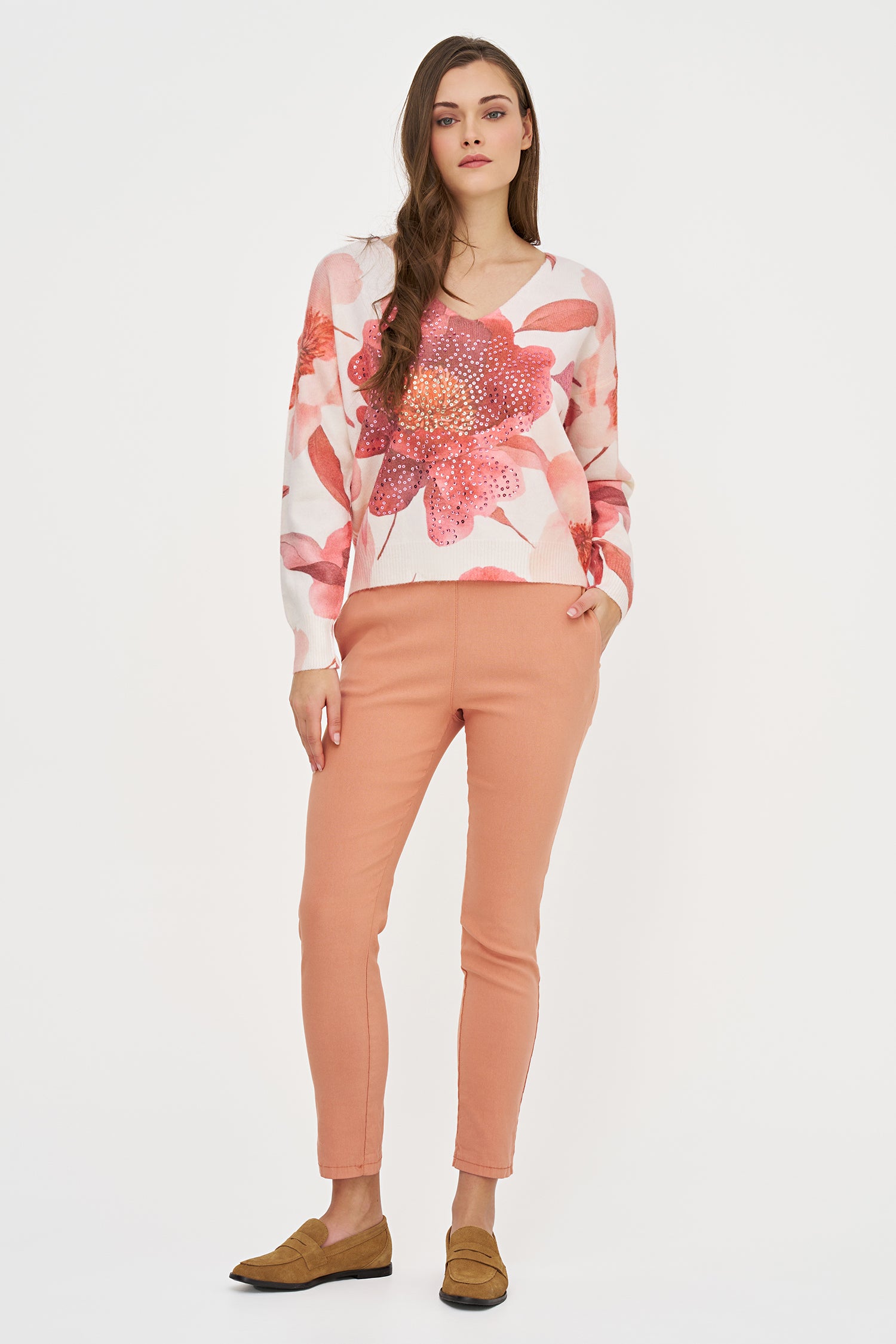 Woman wearing a floral sweater and pink pants on a white background
