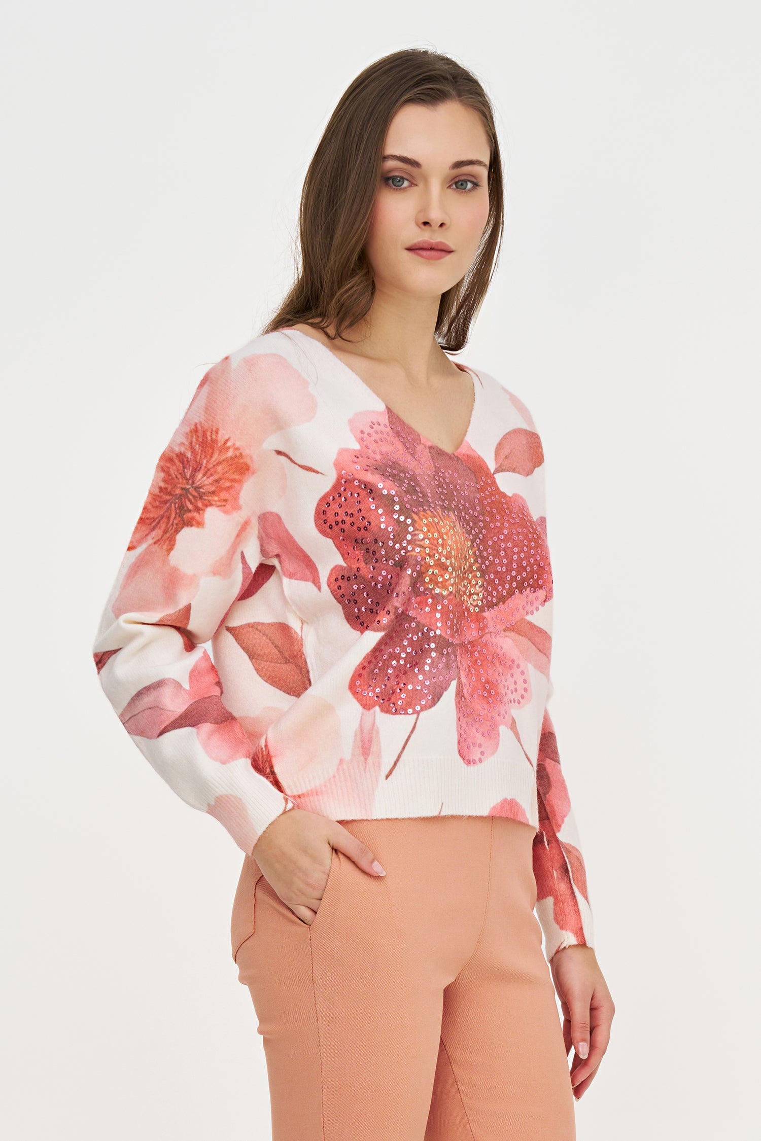 Woman wearing a floral blouse with pink and white flowers on a plain background