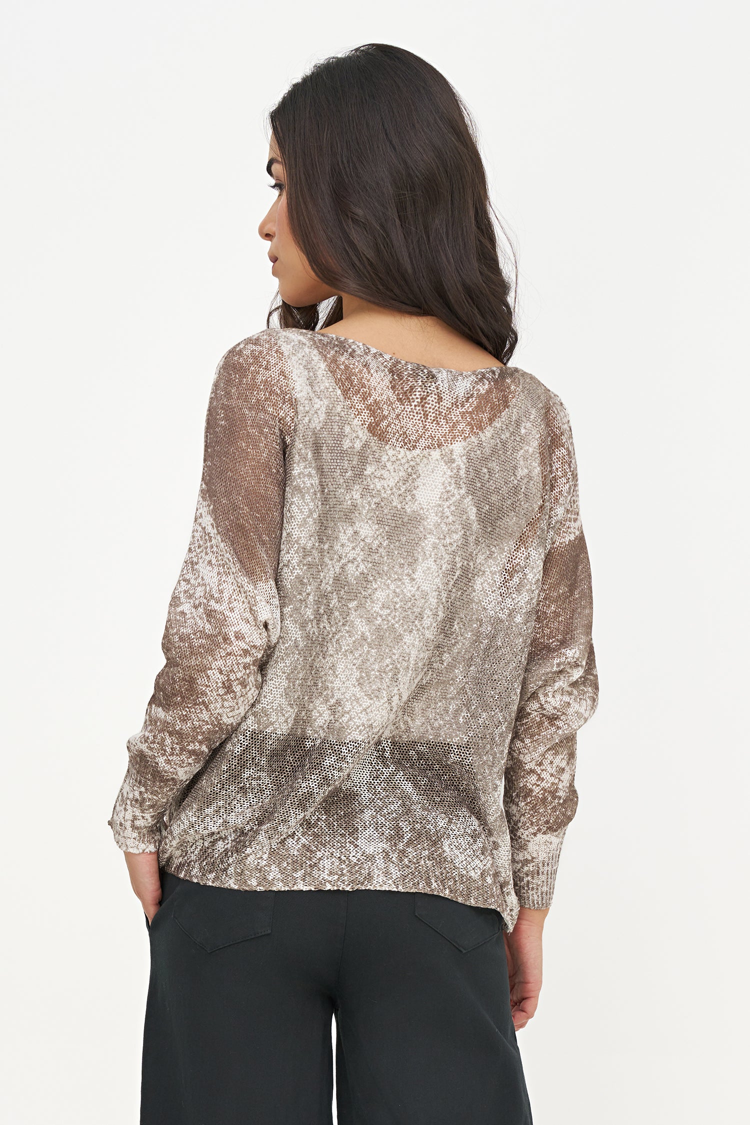 Woman wearing a patterned top with sheer sleeves on a white background