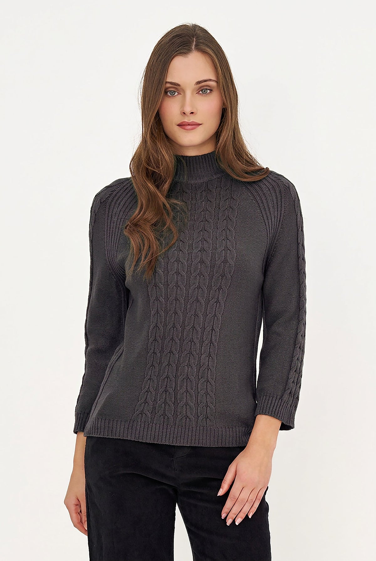 A woman modeling a dark gray cable-knit mock neck sweater with three-quarter sleeves, paired with black pants, against a plain white studio background.