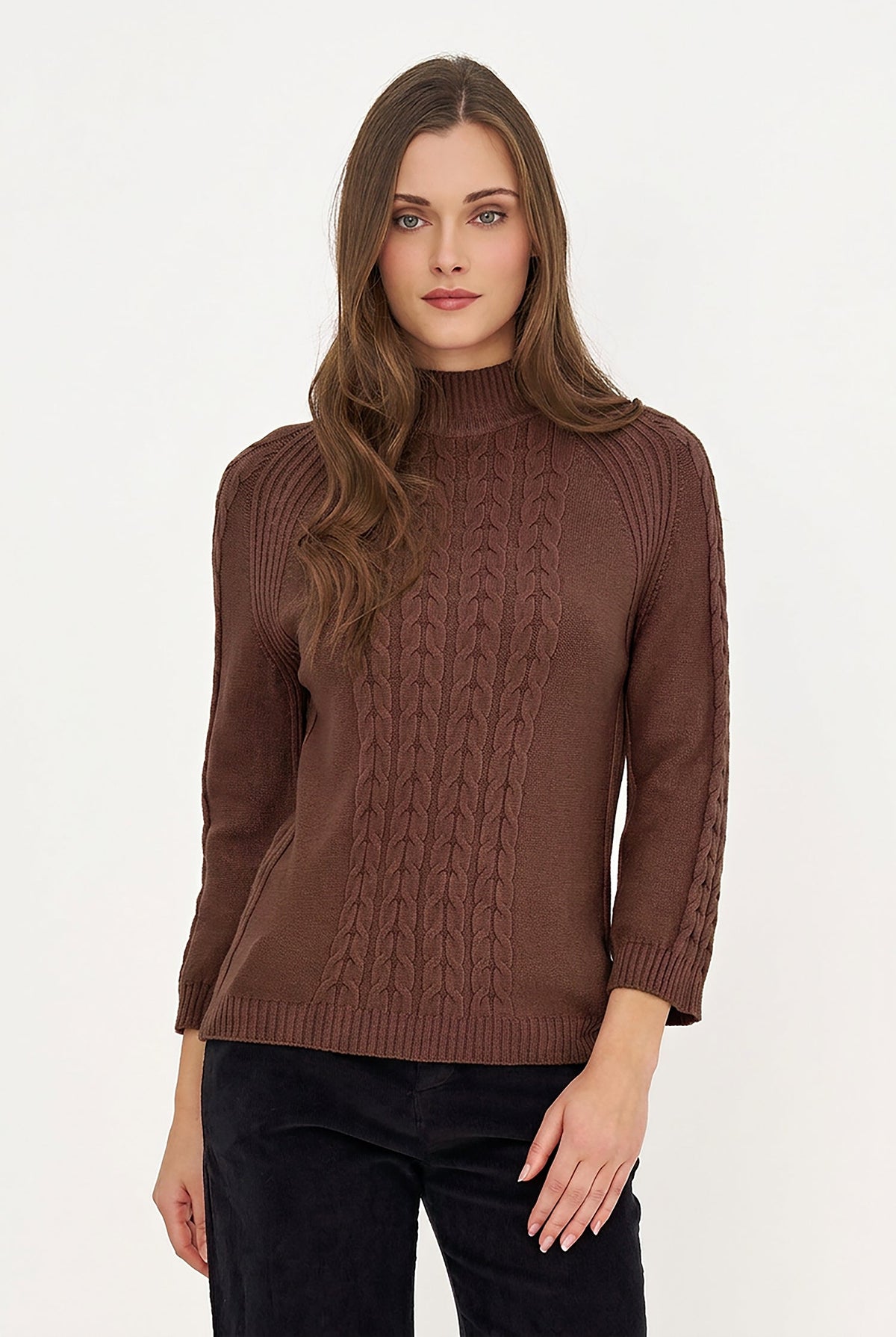 A woman modeling a brown mock-neck cable-knit sweater with three-quarter sleeves, paired with black pants, against a plain white studio background.