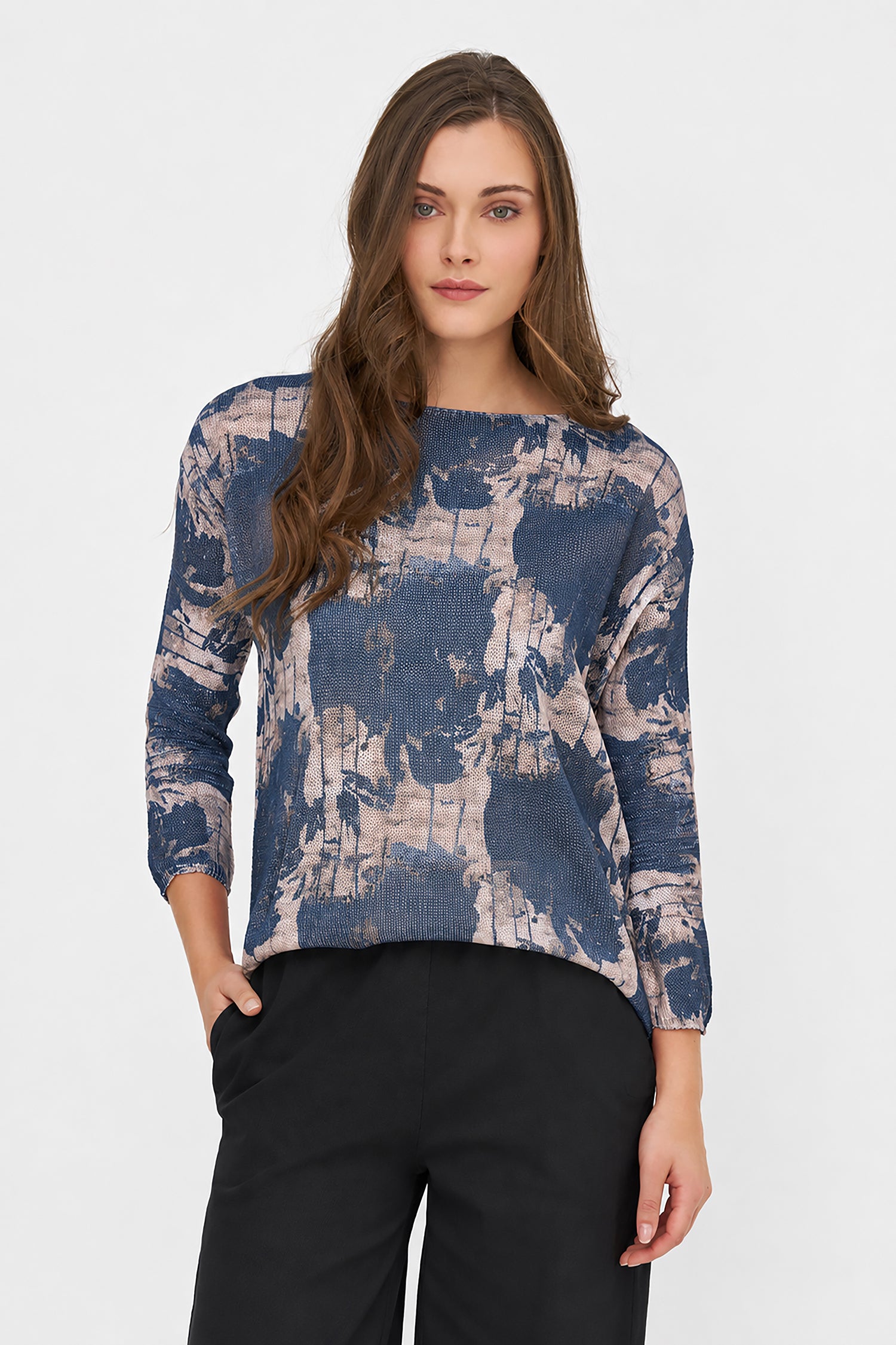 Woman wearing a blue and beige patterned top with black pants on a white background