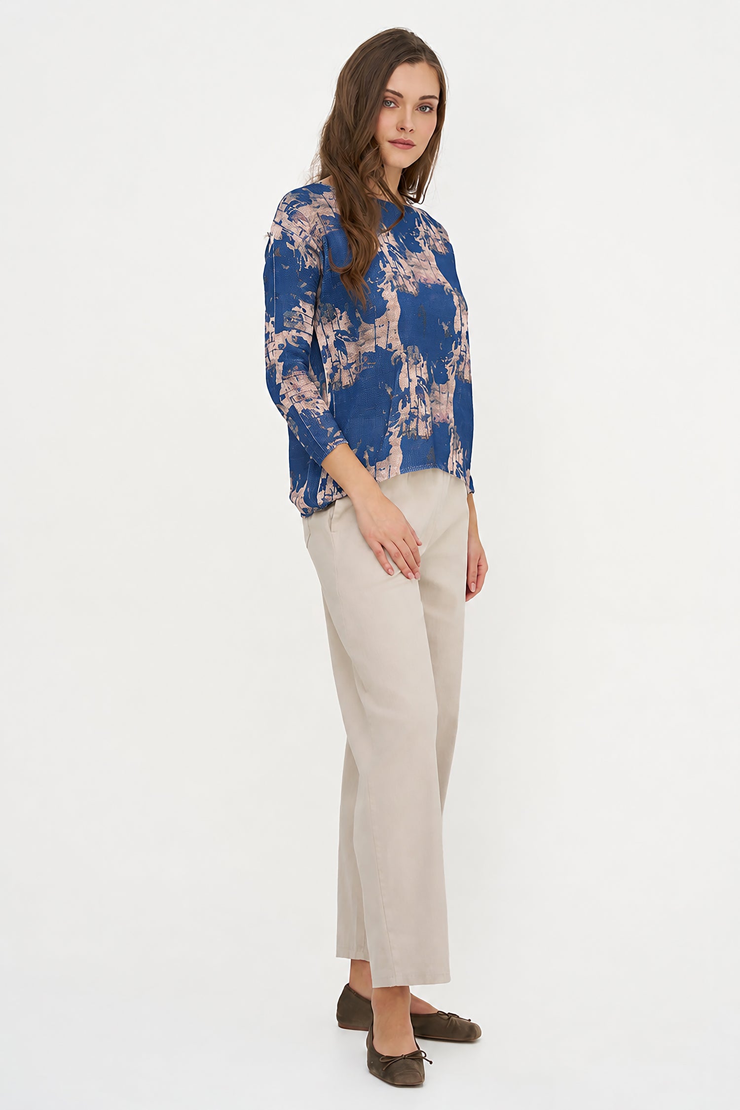 Woman wearing a blue floral blouse and beige pants on a white background