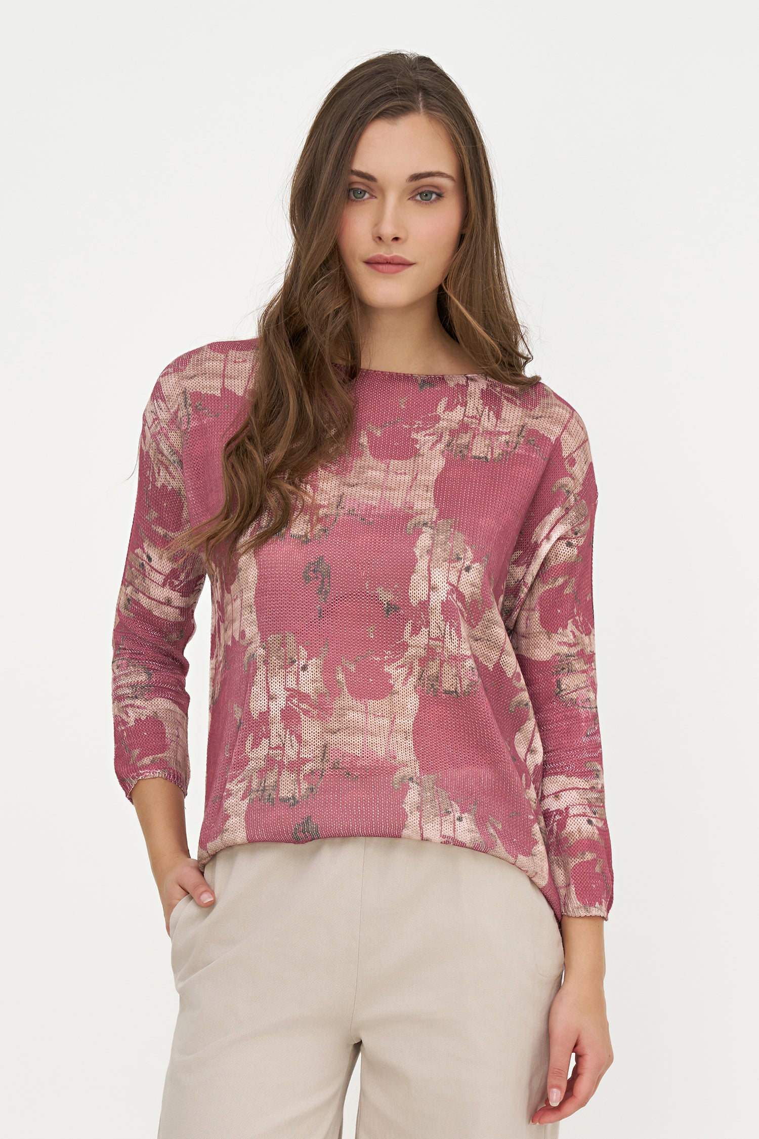 Woman wearing a pink floral top with beige pants on a white background