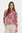 Woman wearing a pink floral top with beige pants on a white background