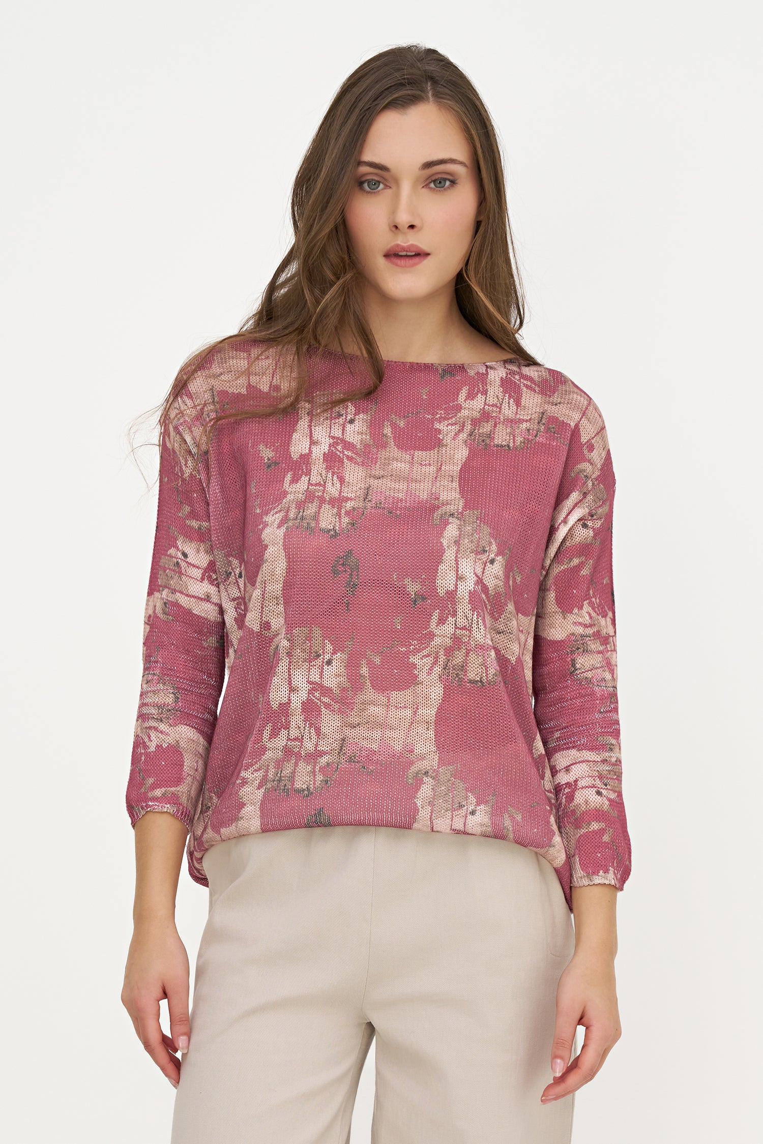 Woman wearing a pink floral blouse with beige pants on a white background