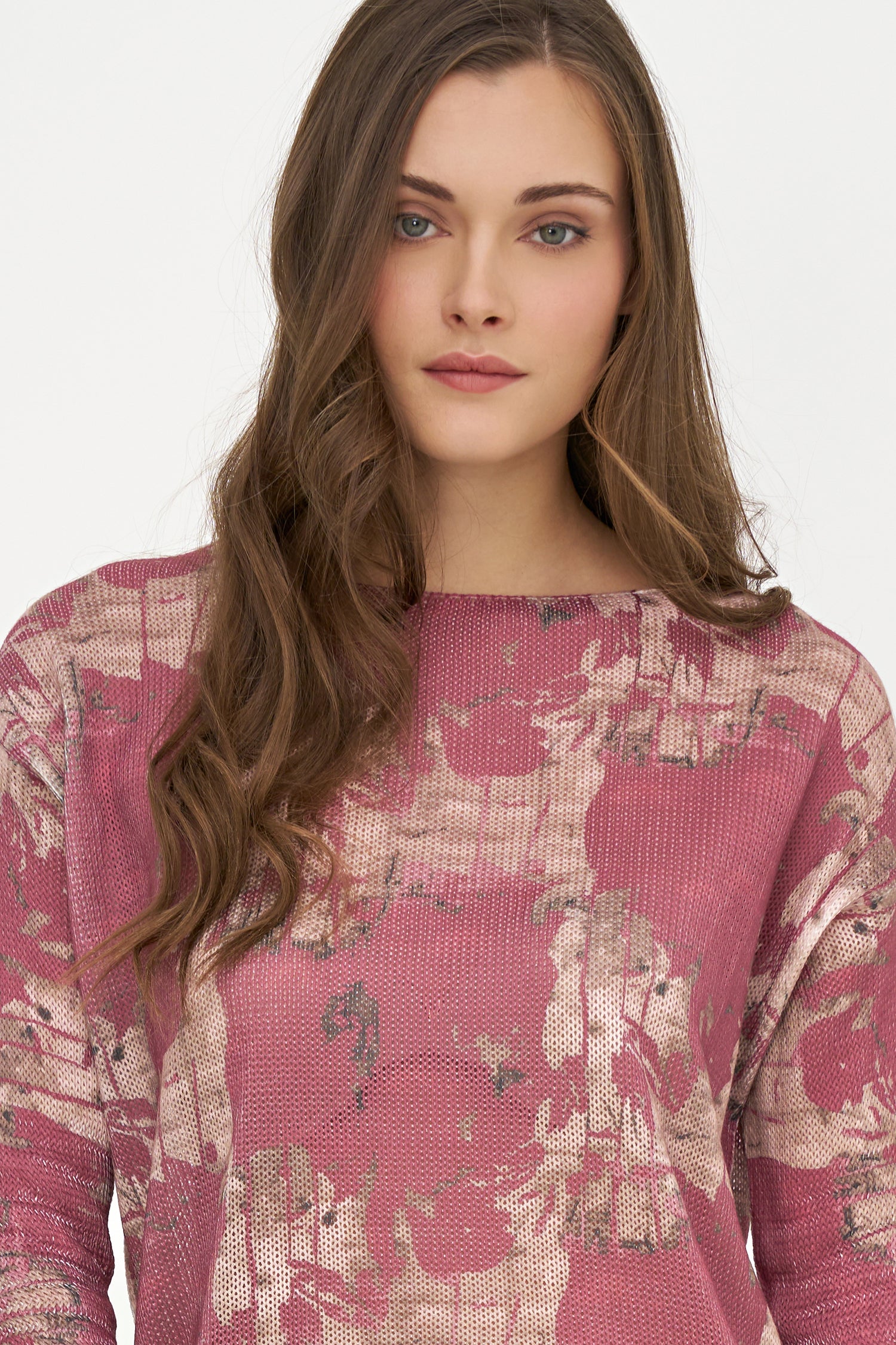 Woman wearing a pink floral patterned sweater on a white background