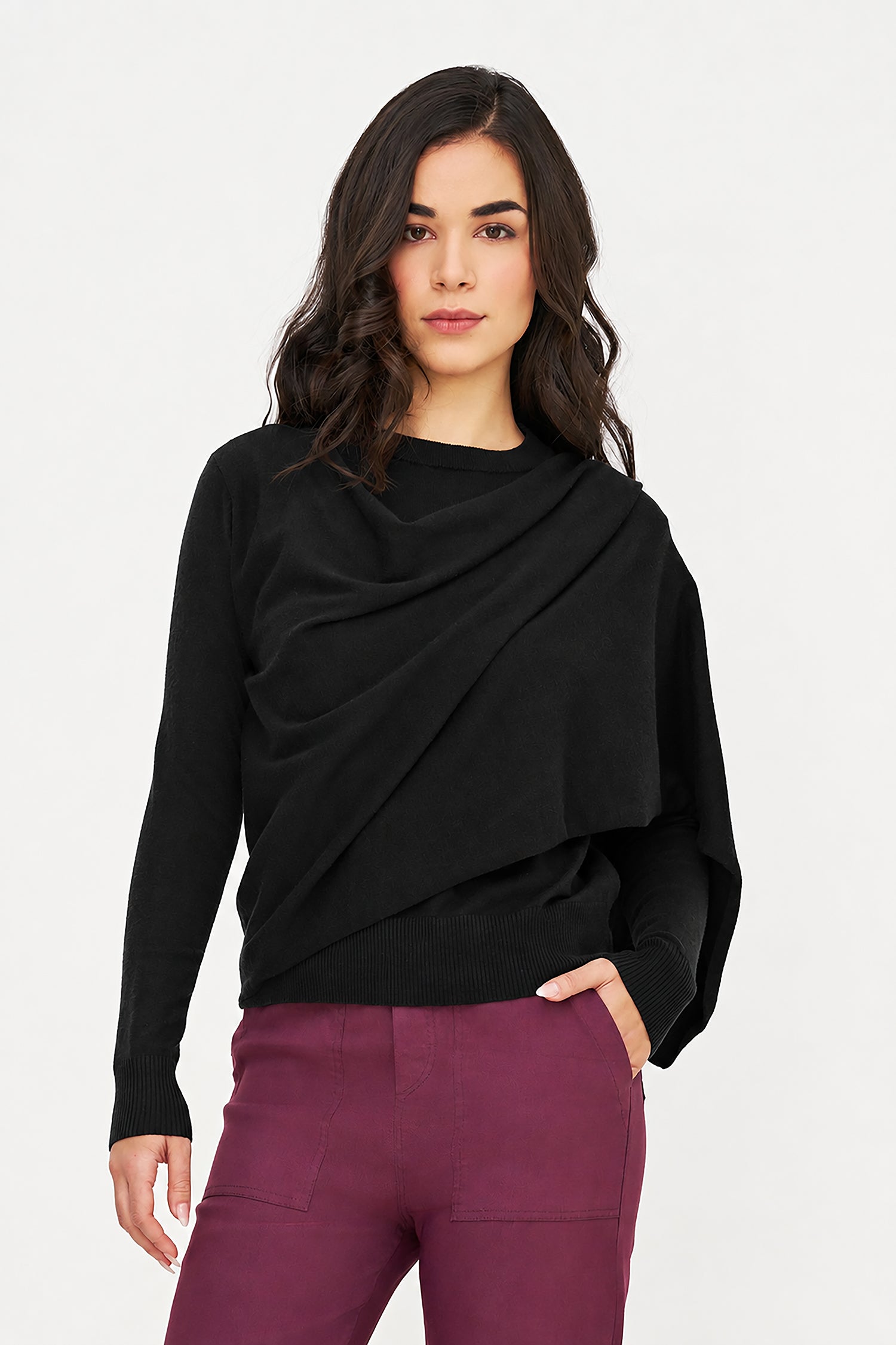 Woman wearing a black draped sweater and purple pants on a white background