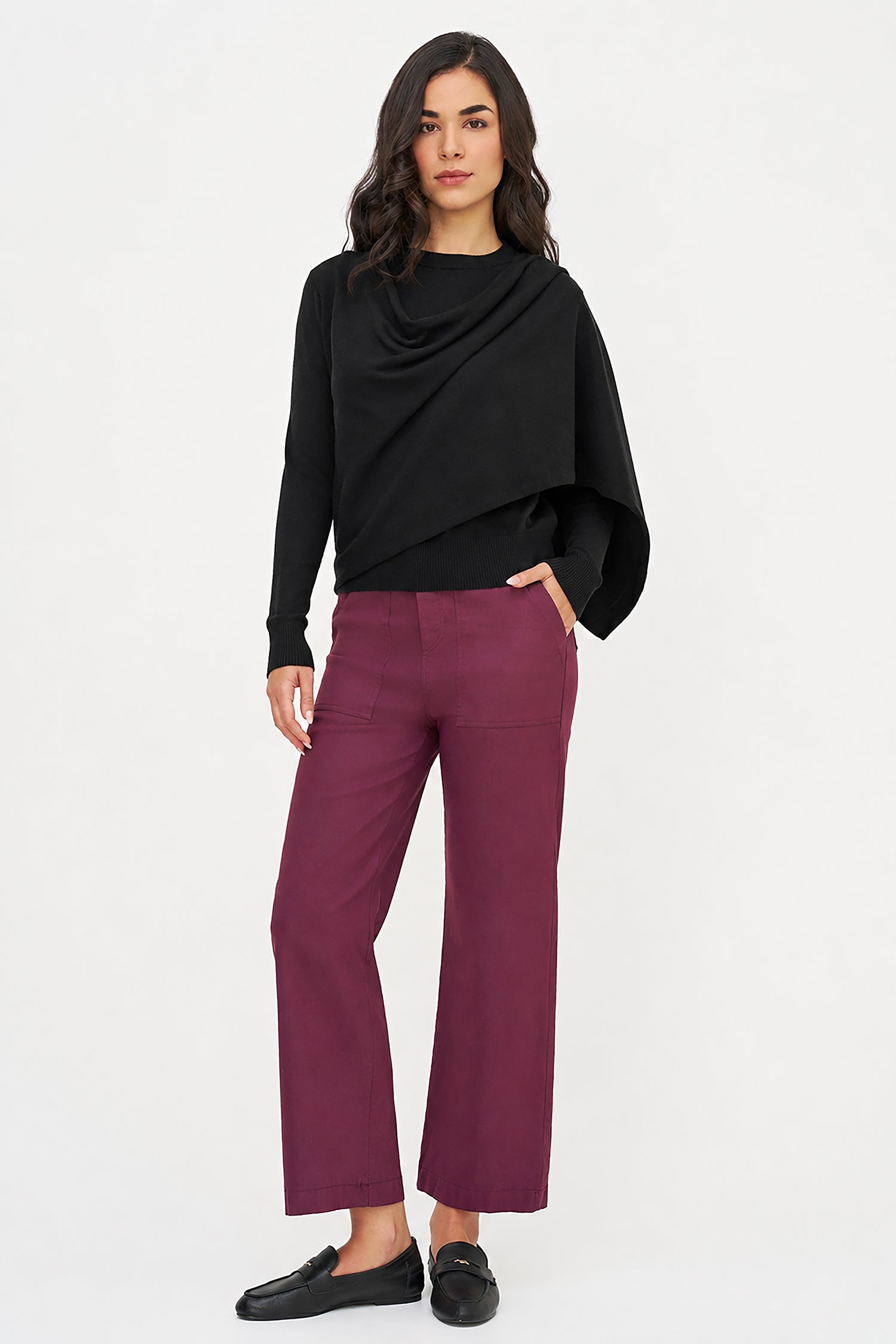 Woman wearing a black top and maroon pants on a white background