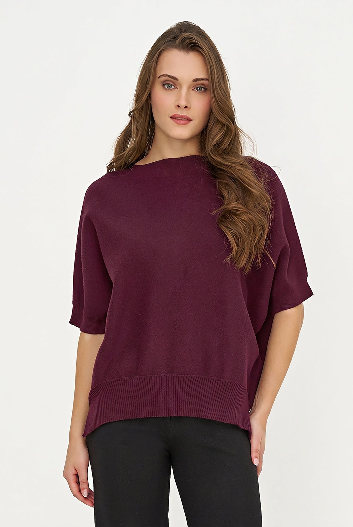 A woman modeling a short-sleeve knit sweater in deep burgundy with a wide boat neckline and ribbed hem, paired with black pants against a plain white studio background.